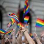 numerous hands waving rainbow flags in celebration